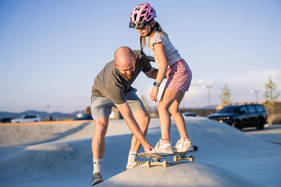 A father teaching his daughter to skateboard at Firefly